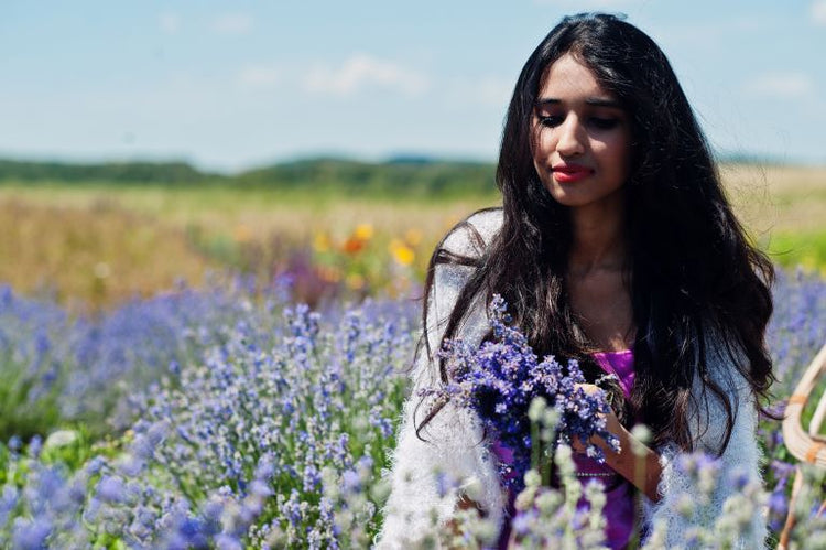 A woman in a field of flowers, symbolizing the brand's commitment to natural ingredients and sustainable wellness.