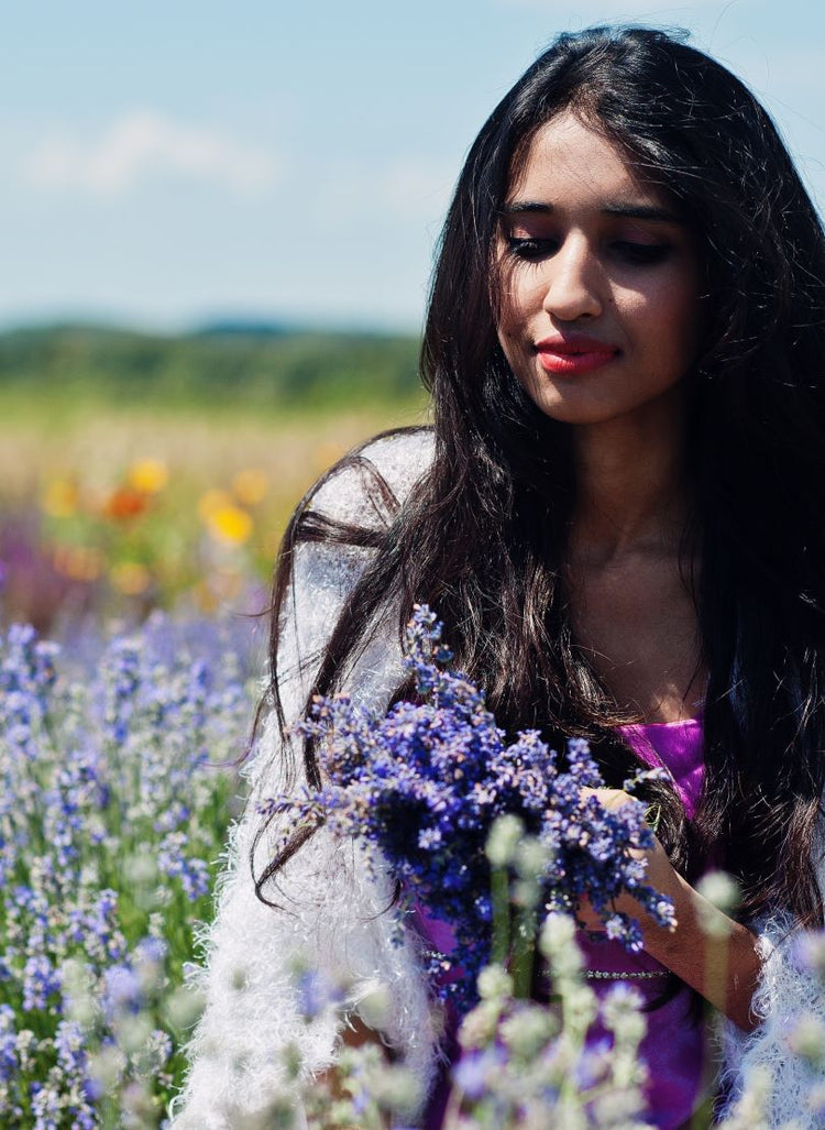 A woman in a field of flowers, symbolizing the brand's commitment to natural ingredients and sustainable wellness.